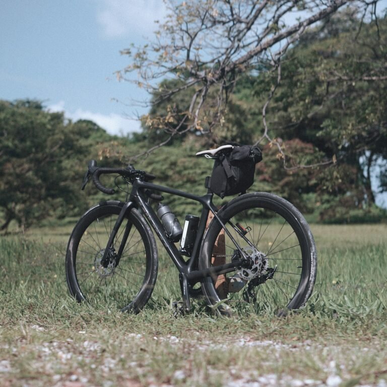 a-bicycle-parked-in-a-field-with-a-backpack-on-the-back